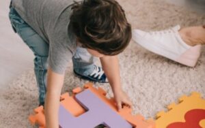 child-playing-with-alphabet-puzzle-mat-on-carpet