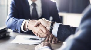 Business professionals shaking hands during a corporate meeting with documents on the table