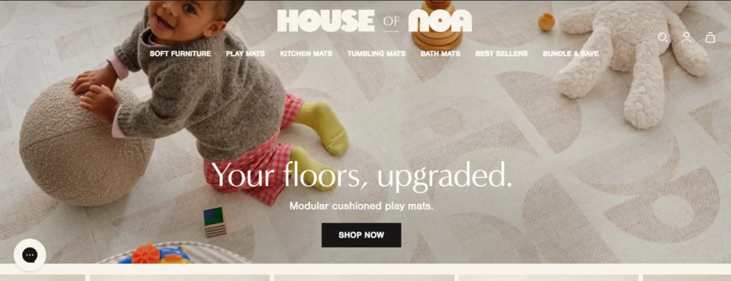 House of Noa homepage banner showing a toddler playing on a modular cushioned play mat with a geometric pattern.